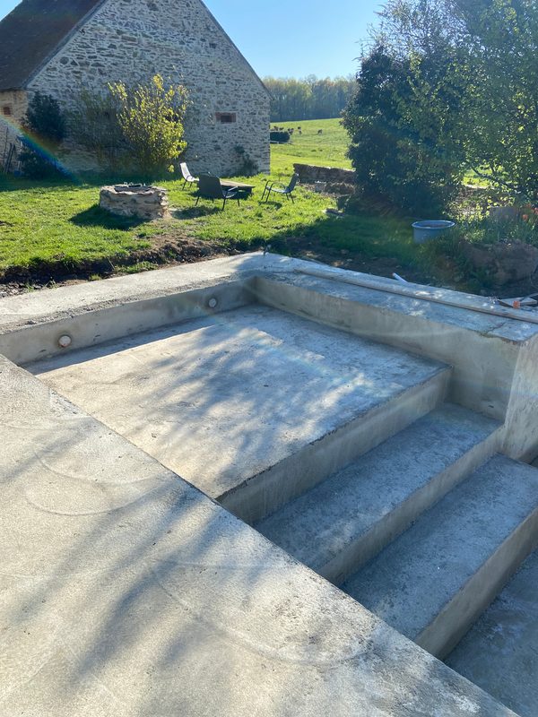 Bassin en béton en construction, jardin et campagne alentour