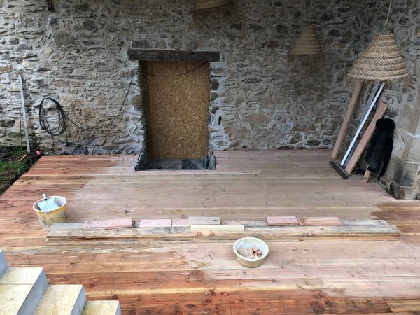 Terrasse en bois posée sur lambourdes, planches empilées au sol