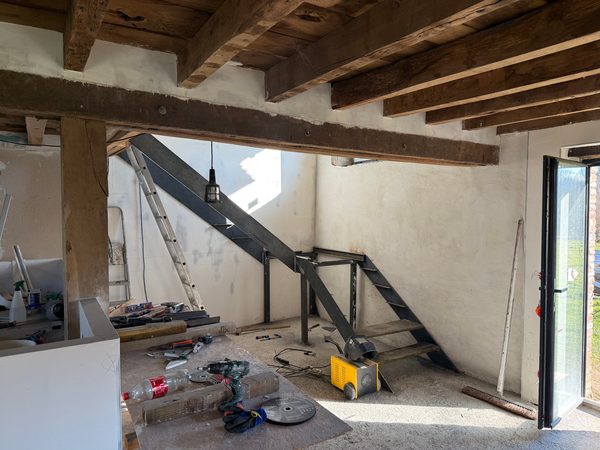 Escalier métallique en cours de pose sous une poutre ancienne