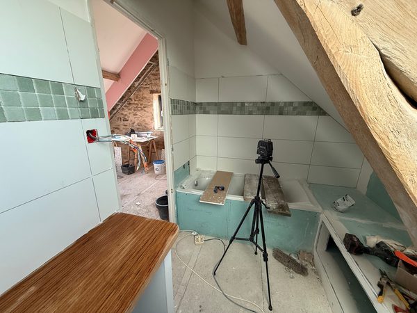 Salle de bain en cours de carrelage sous une charpente en chêne