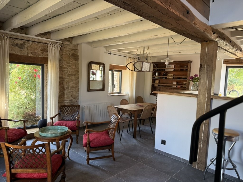 La Bergerie's living/dining room: the dining table and its six chairs near the bar, armchairs in the foreground and a French window open onto the garden